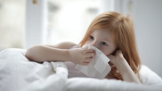 Child blowing her nose in her bed